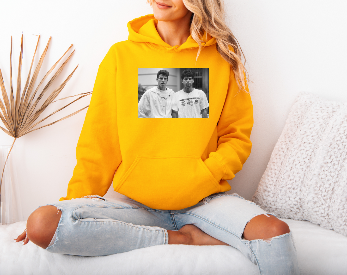 a woman sitting on a bed wearing a yellow hoodie