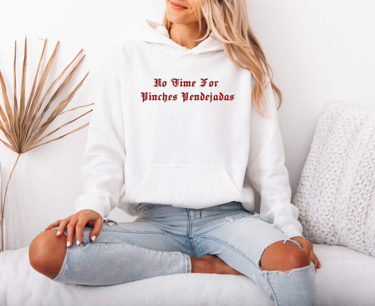 a woman sitting on a couch wearing a white hoodie