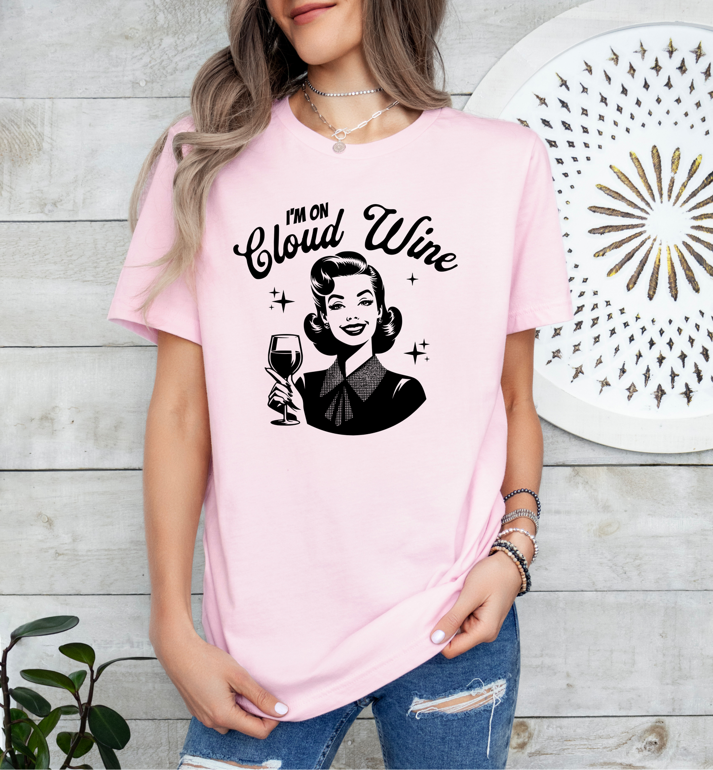 a woman holding a glass of wine wearing a pink shirt