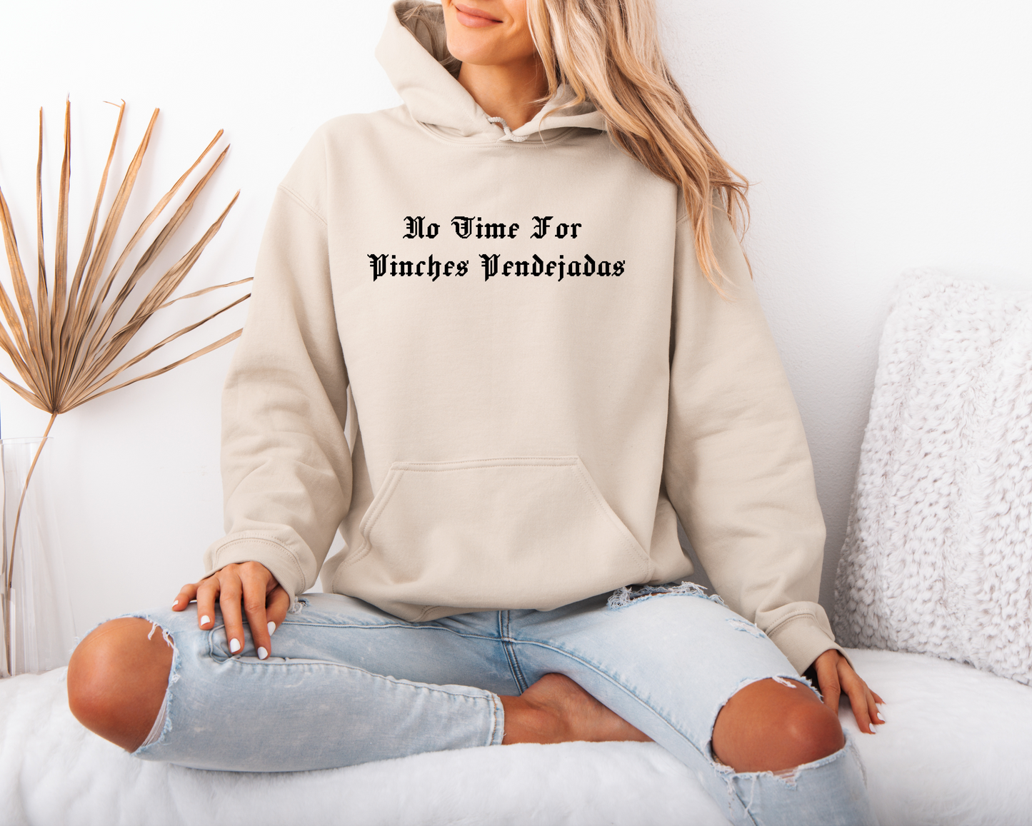 a woman sitting on a bed wearing a hoodie