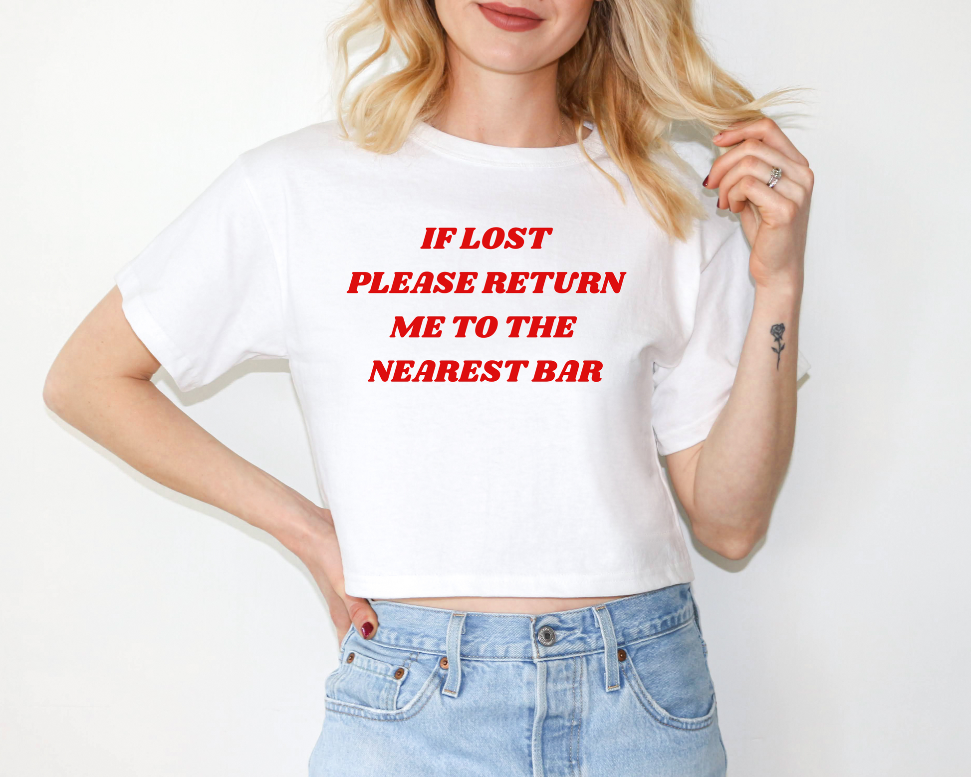 a woman wearing a white shirt that says if lost please return me to the nearest