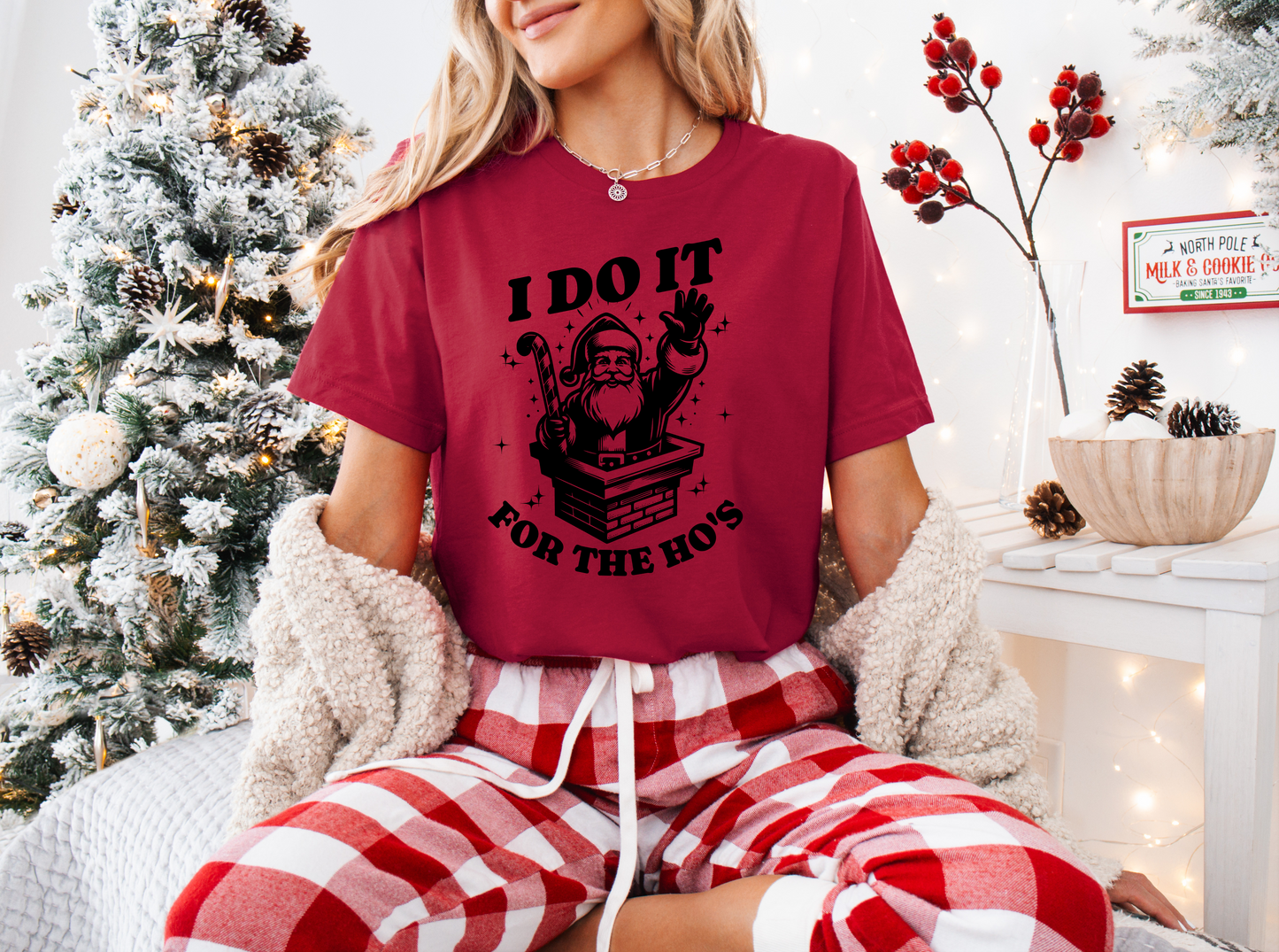 a woman sitting on a bed wearing a red shirt and plaid pants