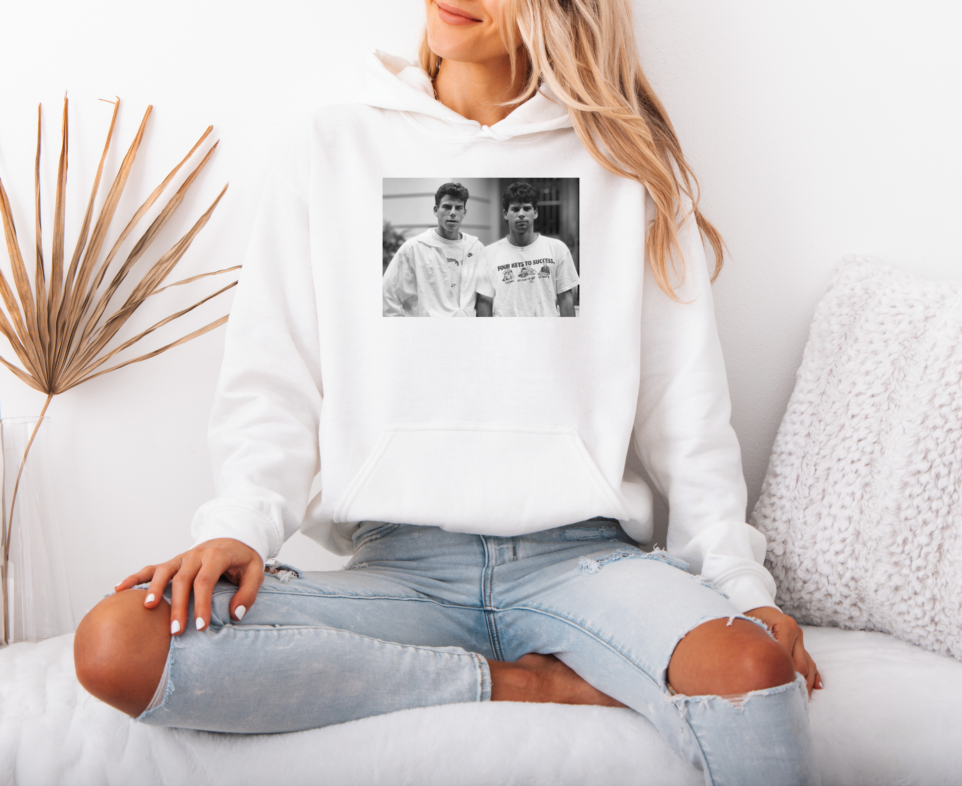 a woman sitting on a couch wearing a white hoodie